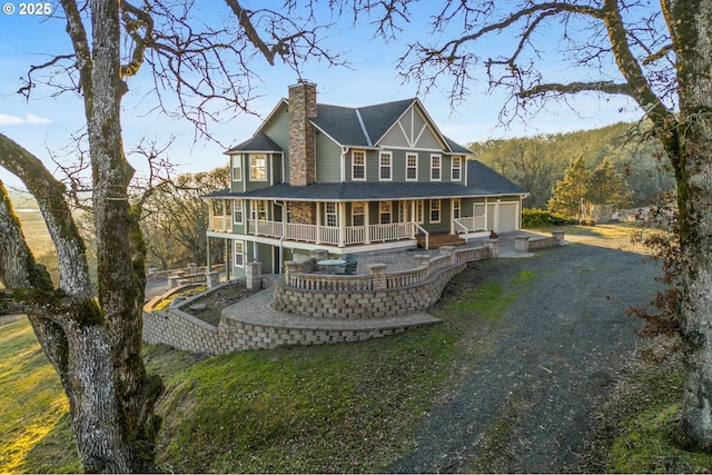 back of property with a garage, covered porch, and a lawn