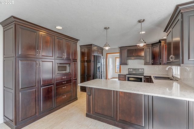 kitchen featuring sink, backsplash, hanging light fixtures, dark brown cabinetry, and stainless steel appliances