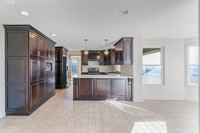 kitchen with dark brown cabinets, stainless steel appliances, sink, and hanging light fixtures