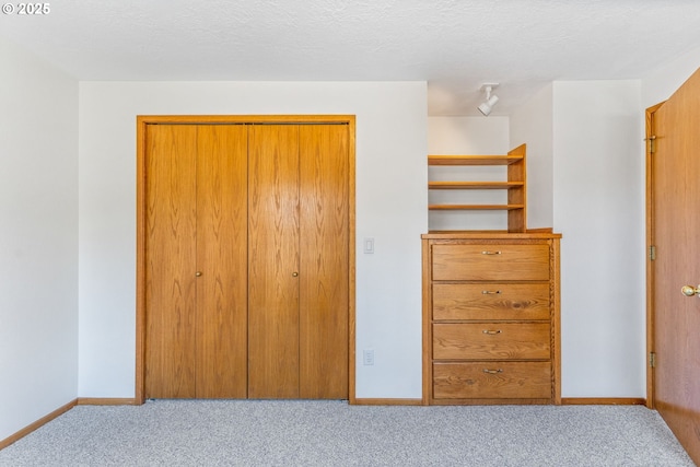 unfurnished bedroom featuring a closet, light carpet, and a textured ceiling