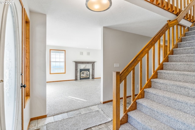 stairway featuring a tiled fireplace and carpet flooring