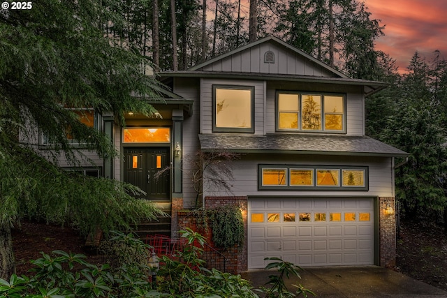 view of front of home with driveway, a shingled roof, an attached garage, board and batten siding, and brick siding