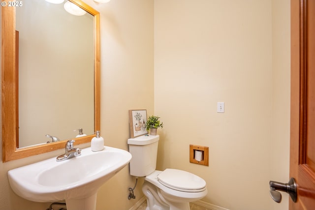 bathroom with baseboards, a sink, and toilet