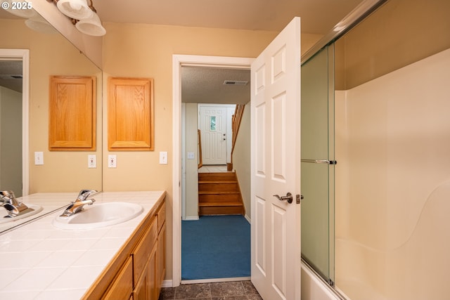 full bathroom with enclosed tub / shower combo, vanity, visible vents, and baseboards