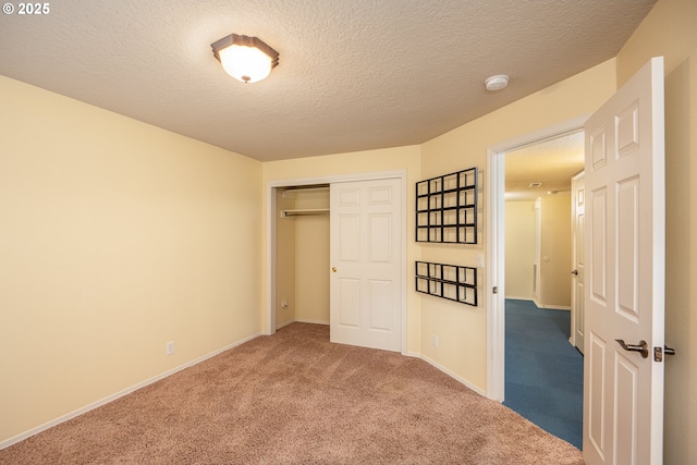 unfurnished bedroom with carpet, a closet, a textured ceiling, and baseboards