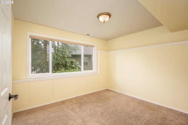 carpeted empty room featuring visible vents and baseboards