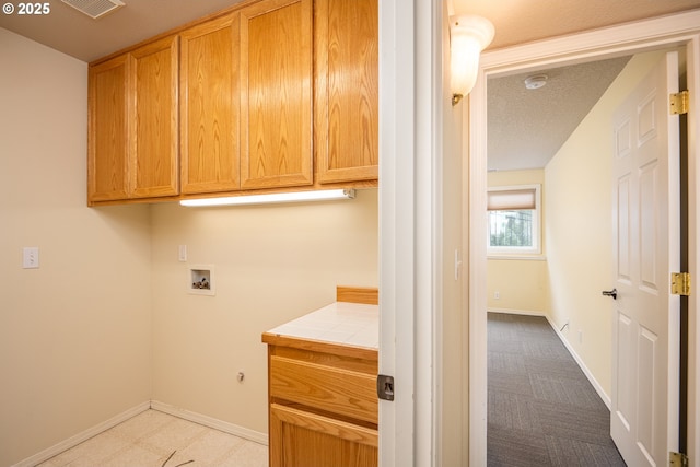 clothes washing area with cabinet space, baseboards, washer hookup, and a textured ceiling