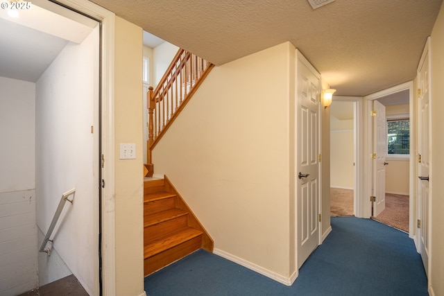 stairs with carpet floors, visible vents, a textured ceiling, and baseboards