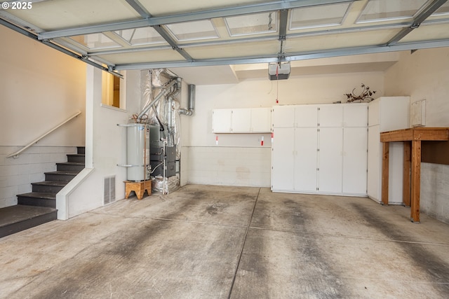 garage with secured water heater, visible vents, and a garage door opener