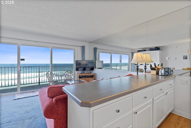 4229 SW Beach Ave Unit 27, Lincoln City, OR 97367 - kitchen with white cabinetry, open floor plan, dark countertops, and a textured ceiling