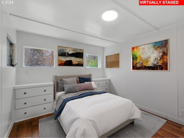bedroom with dark wood-type flooring and baseboards