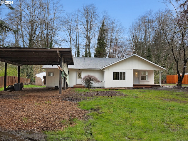 view of front of house featuring a front lawn, roof with shingles, fence, and an attached carport