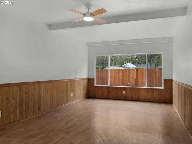 unfurnished room featuring wainscoting, wooden walls, and a healthy amount of sunlight