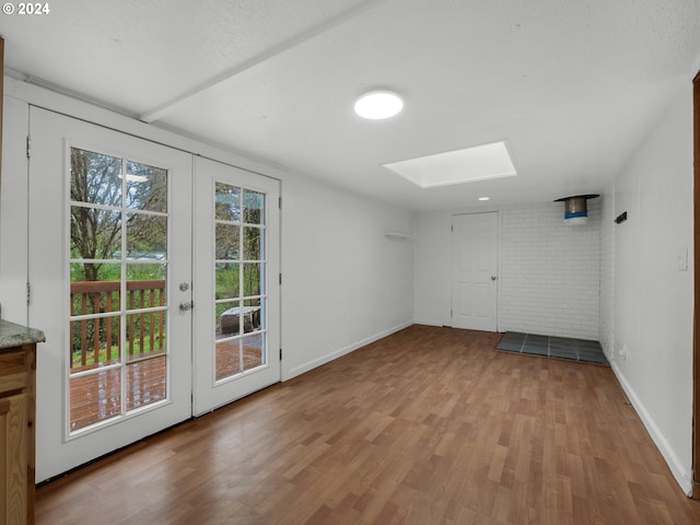 interior space with a skylight, baseboards, french doors, and wood finished floors