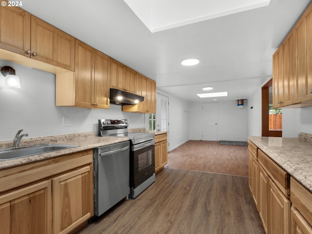 kitchen featuring dark wood-style flooring, appliances with stainless steel finishes, a sink, light countertops, and under cabinet range hood