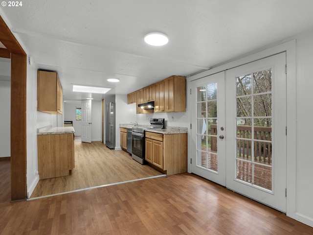 kitchen with appliances with stainless steel finishes, light countertops, baseboards, under cabinet range hood, and light wood-style flooring