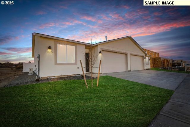 1201 NE Emerald Dr, Hermiston, OR 97838 - view of front of property with an attached garage, concrete driveway, a front yard, and stucco siding