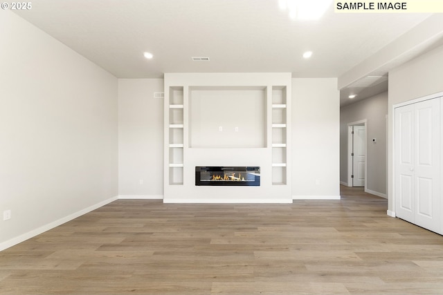 1201 NE Emerald Dr, Hermiston, OR 97838 - unfurnished living room with recessed lighting, wood finished floors, a glass covered fireplace, and built in features