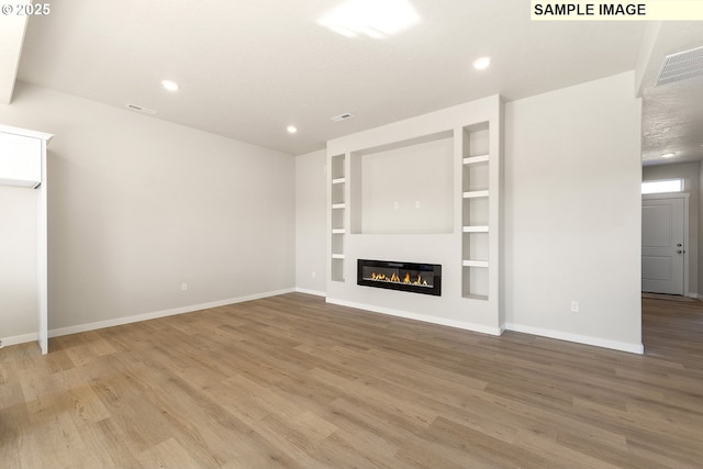 1201 NE Emerald Dr, Hermiston, OR 97838 - unfurnished living room with light wood finished floors, recessed lighting, a glass covered fireplace, and built in shelves
