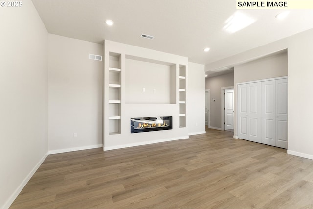 1201 NE Emerald Dr, Hermiston, OR 97838 - unfurnished living room featuring wood finished floors, a glass covered fireplace, recessed lighting, and built in features