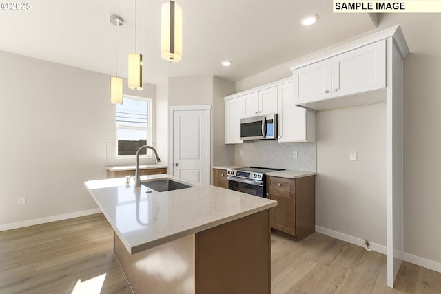 1201 NE Emerald Dr, Hermiston, OR 97838 - kitchen with stainless steel appliances, tasteful backsplash, light wood finished floors, an island with sink, and white cabinets
