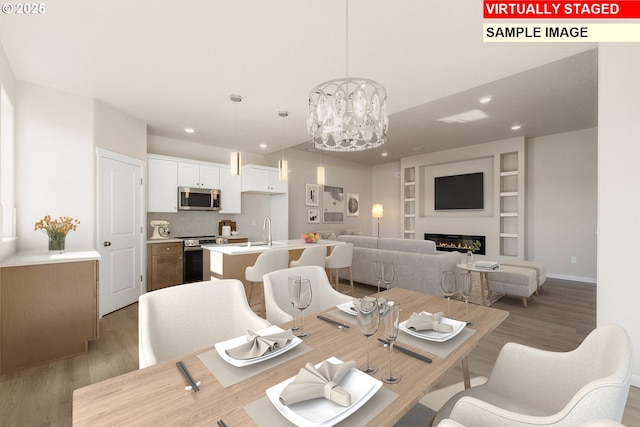 1201 NE Emerald Dr, Hermiston, OR 97838 - dining area with light wood-style flooring, a chandelier, recessed lighting, built in shelves, and a glass covered fireplace