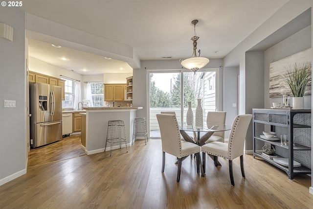 dining space with light wood-type flooring and sink