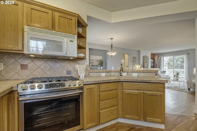 kitchen with backsplash, kitchen peninsula, pendant lighting, wood-type flooring, and stainless steel stove