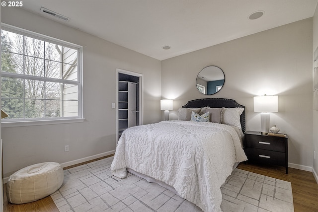 bedroom featuring wood-type flooring, a spacious closet, and a closet