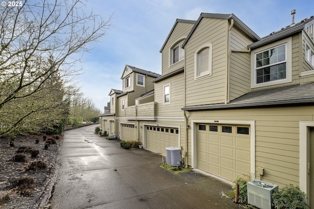 view of side of property featuring ac unit, a garage, and cooling unit