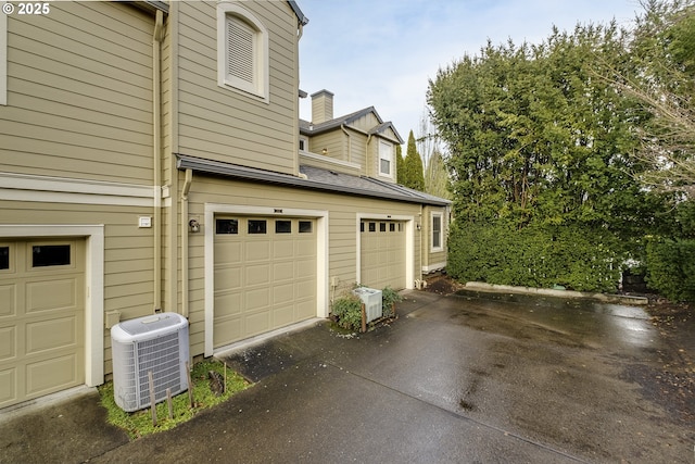 view of side of property featuring central AC unit and a garage