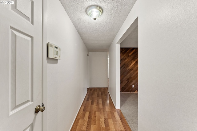 hallway with a textured ceiling and light hardwood / wood-style flooring