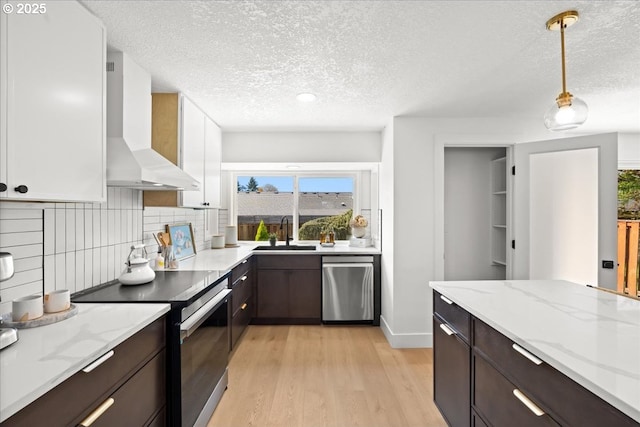 kitchen with black electric range oven, wall chimney range hood, dishwasher, a sink, and dark brown cabinets