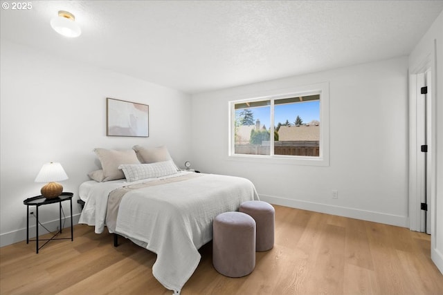 bedroom featuring light wood finished floors and baseboards
