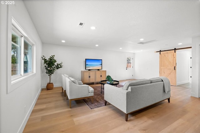 living room with a barn door, light wood-style flooring, recessed lighting, and baseboards
