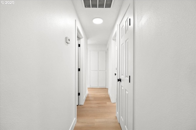 corridor featuring light wood-type flooring and baseboards