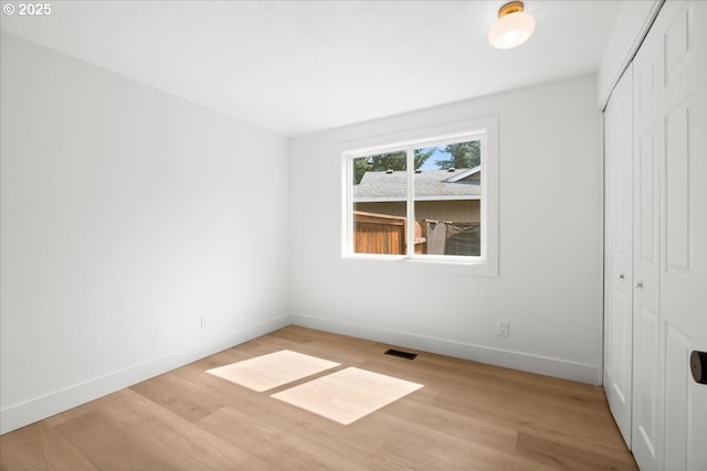 unfurnished bedroom with a closet, wood finished floors, and baseboards