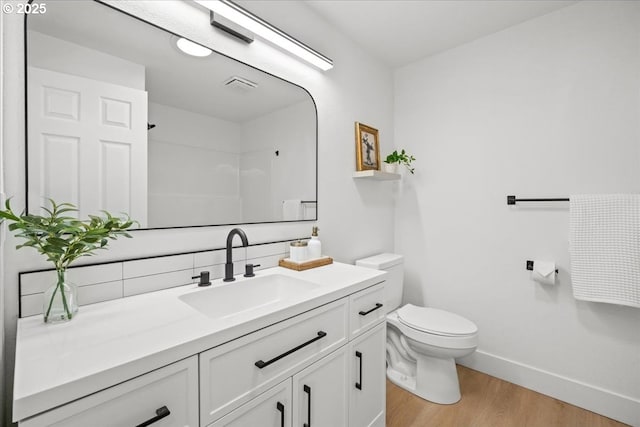 bathroom featuring baseboards, wood finished floors, toilet, and vanity