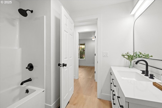 bathroom featuring shower / bath combination, wood finished floors, vanity, and baseboards