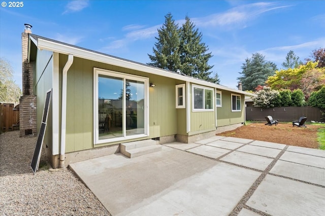 rear view of property with fence, a patio area, entry steps, and a chimney