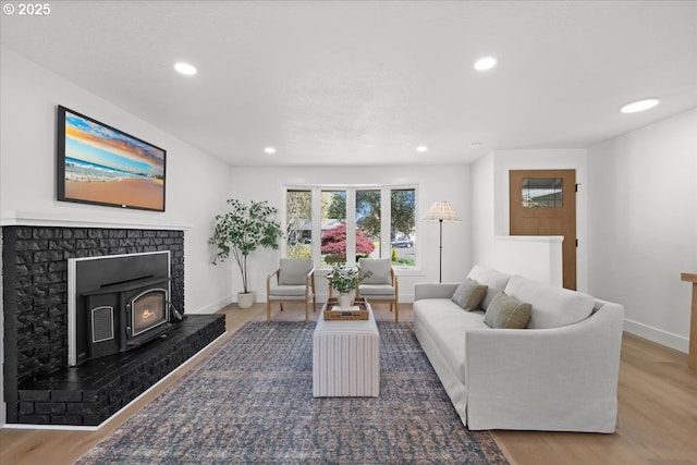 living room with wood finished floors, recessed lighting, a brick fireplace, and baseboards