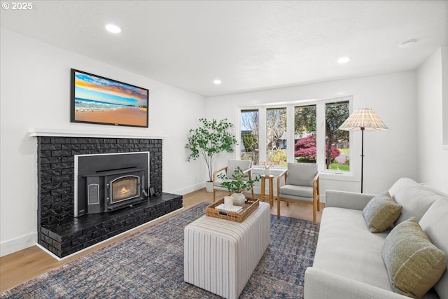 living area featuring wood finished floors, baseboards, recessed lighting, and a brick fireplace