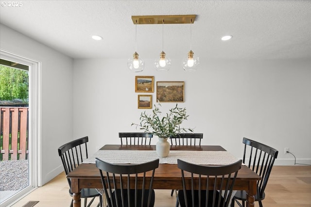 dining space featuring light wood-type flooring, a textured ceiling, recessed lighting, and baseboards