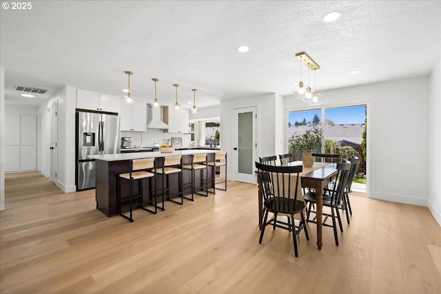 dining area featuring light wood finished floors, plenty of natural light, baseboards, a textured ceiling, and recessed lighting