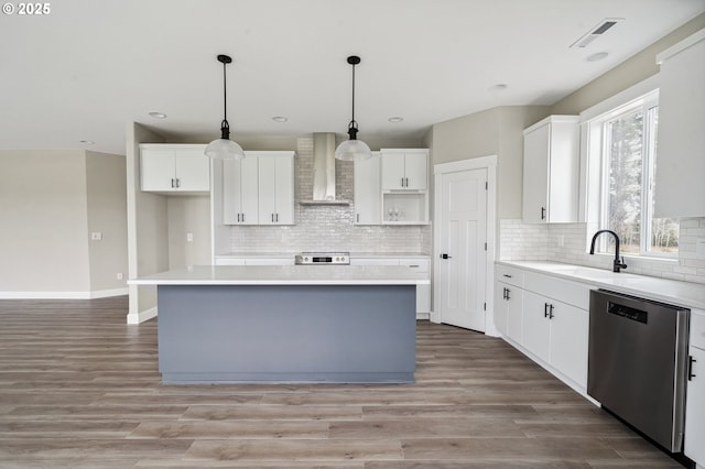 kitchen featuring white cabinetry, stainless steel dishwasher, wall chimney exhaust hood, and a center island