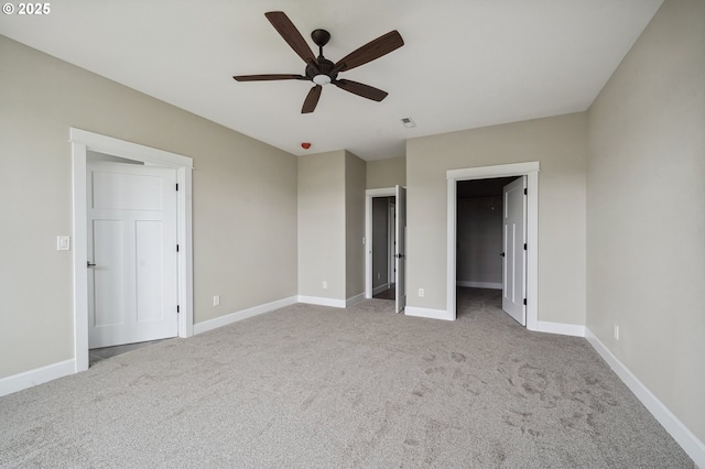 unfurnished bedroom featuring ceiling fan, a spacious closet, and light carpet