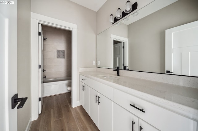 full bathroom with vanity, wood-type flooring, toilet, and tiled shower / bath