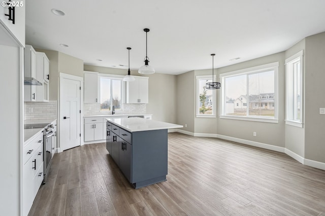 kitchen with white cabinetry, a kitchen island, pendant lighting, and electric stove