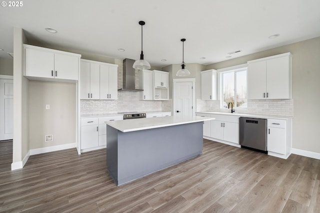 kitchen featuring appliances with stainless steel finishes, a kitchen island, white cabinets, and wall chimney exhaust hood