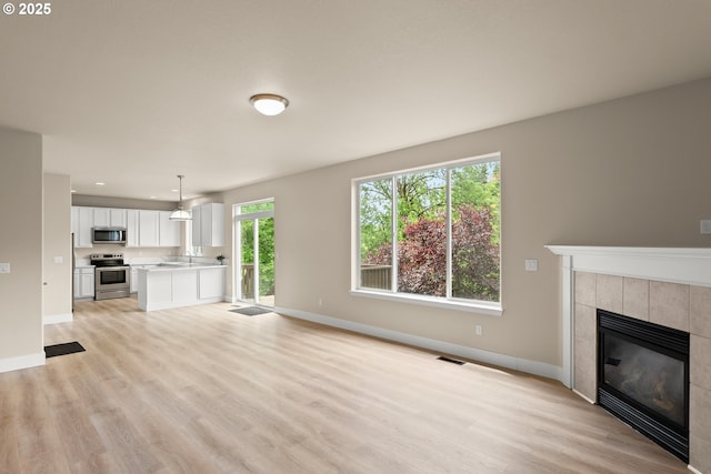 111 SE 49th Ct, Hillsboro, OR 97123 - unfurnished living room featuring a tile fireplace, light wood-style flooring, baseboards, a sink, and recessed lighting